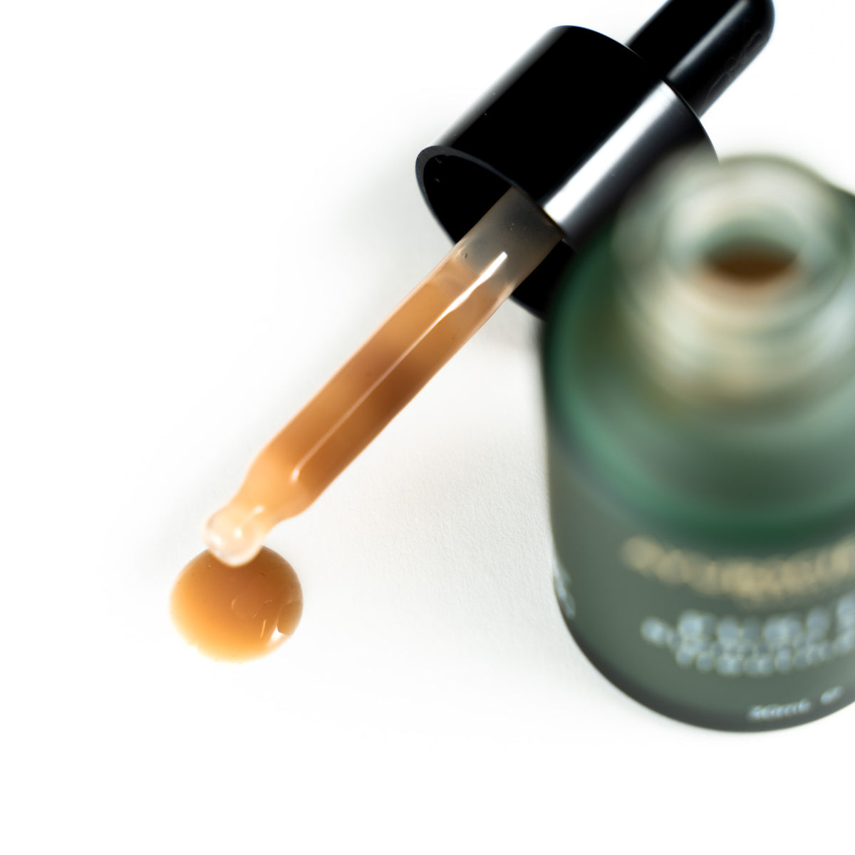 Dropper showing liquid from AyurScience Beauty purity blemish spot treament. Liquid serum is of a pale golden brown colour.